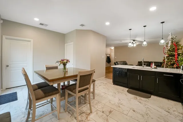 a kitchen with granite countertop a dining table chairs cabinets and stainless steel appliances