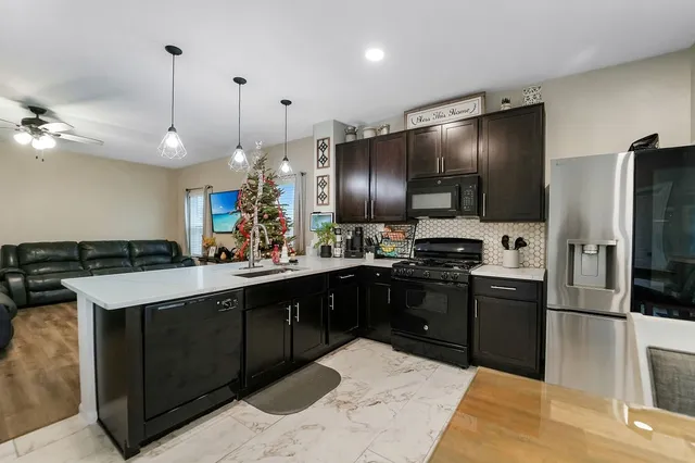 a kitchen with stainless steel appliances kitchen island granite countertop a sink stove and refrigerator