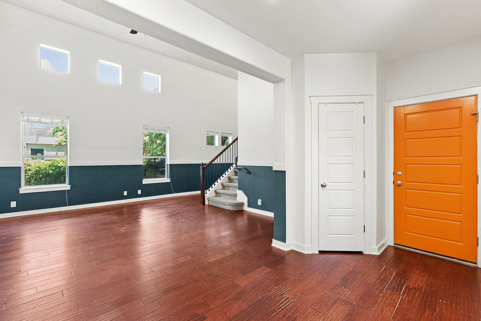 Rich hardwood flooring complements soaring high ceilings in this open-concept entrance hall.