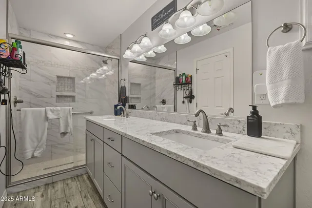 a bathroom with a granite countertop sink a mirror and shower