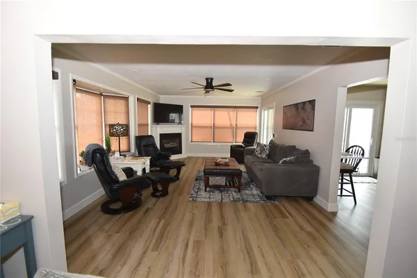 a living room with furniture two large window and wooden floor