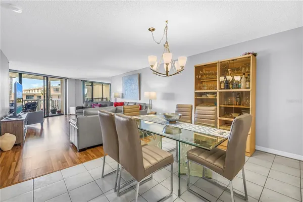 a dining room with wooden floor a chandelier a glass table and chairs