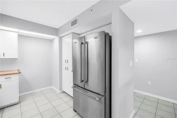 a view of a refrigerator in kitchen and an empty room