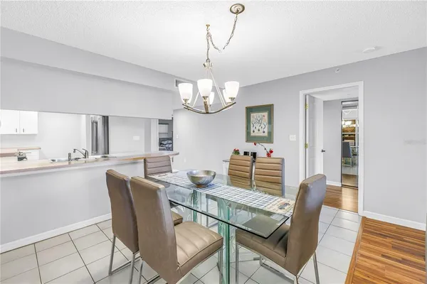 a dining room with wooden floor a chandelier a glass table and chairs