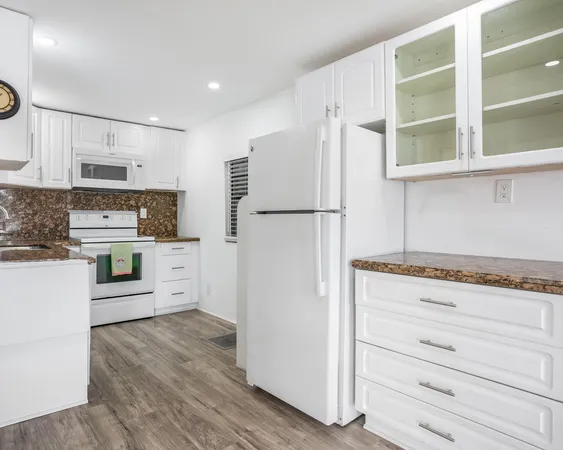 a kitchen with white cabinets and refrigerator
