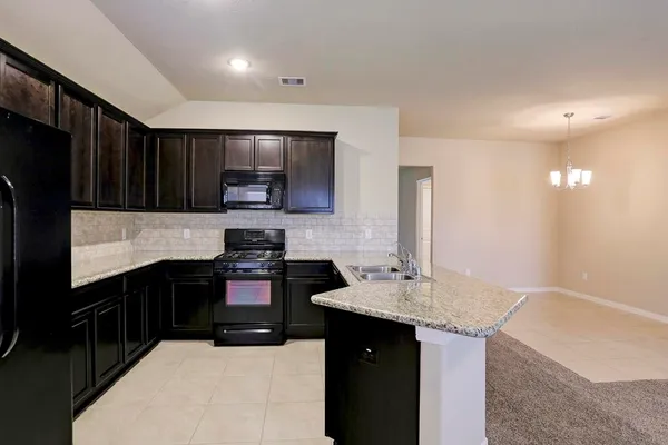 a kitchen with granite countertop stainless steel appliances a sink stove and refrigerator