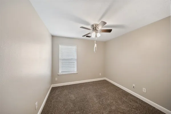 an empty room with a chandelier fan and windows