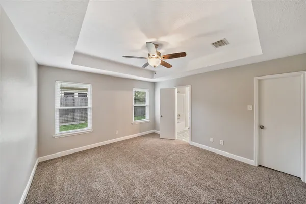 an empty room with ceiling fan and windows