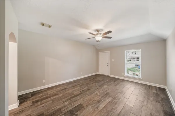 a view of an empty room with wooden floor and a window