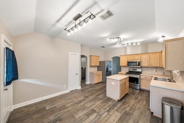a kitchen with a sink a counter top space stainless steel appliances and cabinets