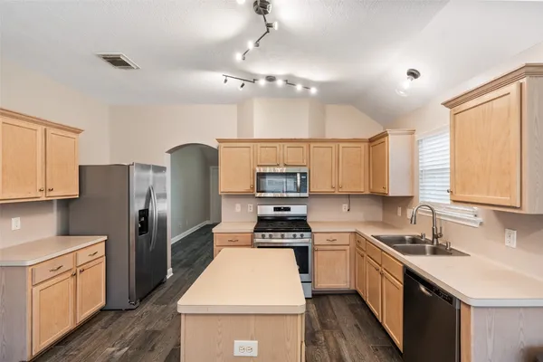 a kitchen with a sink a counter top space stainless steel appliances and cabinets