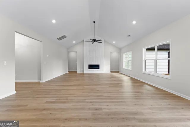 a view of an empty room with window and wooden floor
