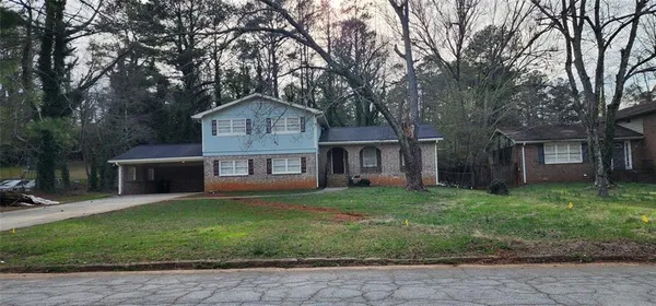 a front view of a house with a garden and trees