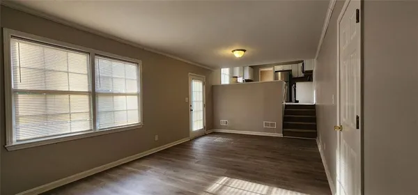 an empty room with wooden floor fireplace and windows