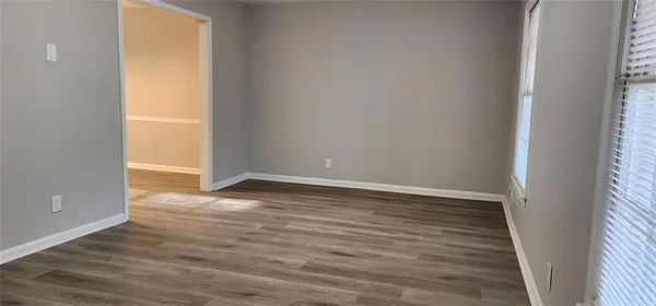 a view of an empty room with wooden floor and a window