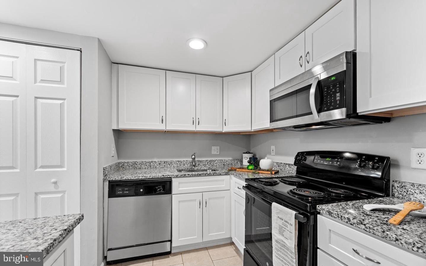 1124 25th Street Northwest, Unit T4 Washington, DC 20037 - Photo 15 of 21 a kitchen with stainless steel appliances granite countertop white cabinets and black stove top oven with granite countertops