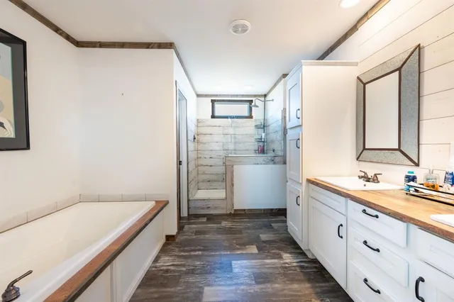 a bathroom with a double vanity sink a mirror and a bathtub