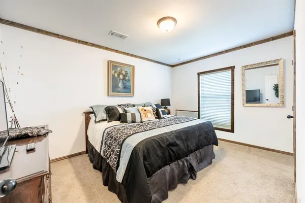 a spacious bedroom with a bed and a flat tv screen on the dresser