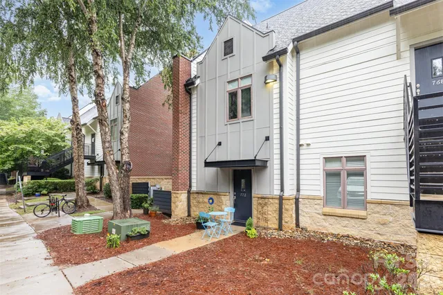a view of a white house with a small yard and large tree