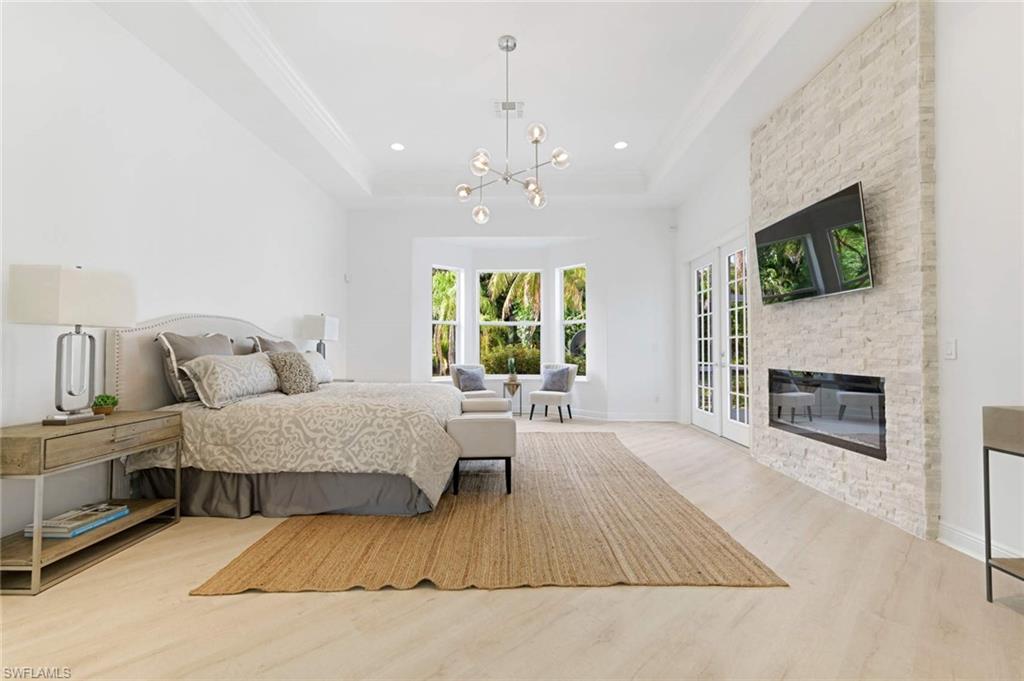 669 West Street Naples, FL 34108 - Photo 15 of 22 a spacious bedroom with a large bed and a fireplace