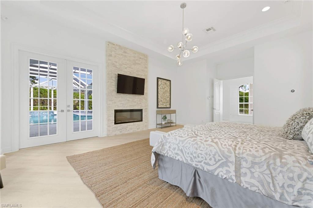 669 West Street Naples, FL 34108 - Photo 16 of 22 a spacious bedroom with a large bed a flat tv screen and a fireplace