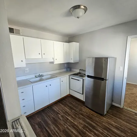 a kitchen with granite countertop a refrigerator and a stove top oven