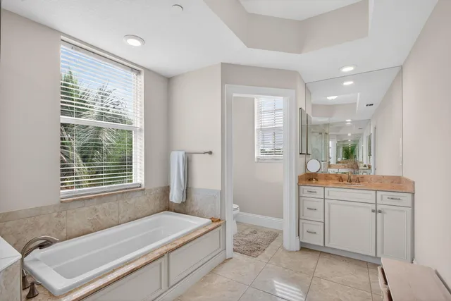 a bathroom with a granite countertop tub a sink and a large mirror