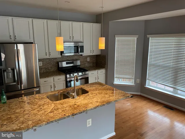 a kitchen with stainless steel appliances granite countertop a sink a stove and a refrigerator