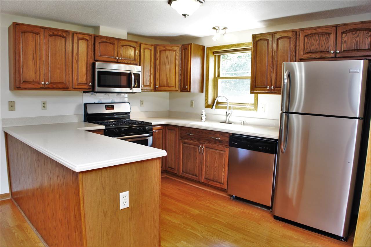 308 Pembroke Road Southwest Poplar Grove, IL 61065 - Photo 6 of 25 a kitchen with a refrigerator a stove a sink and dishwasher with wooden floor