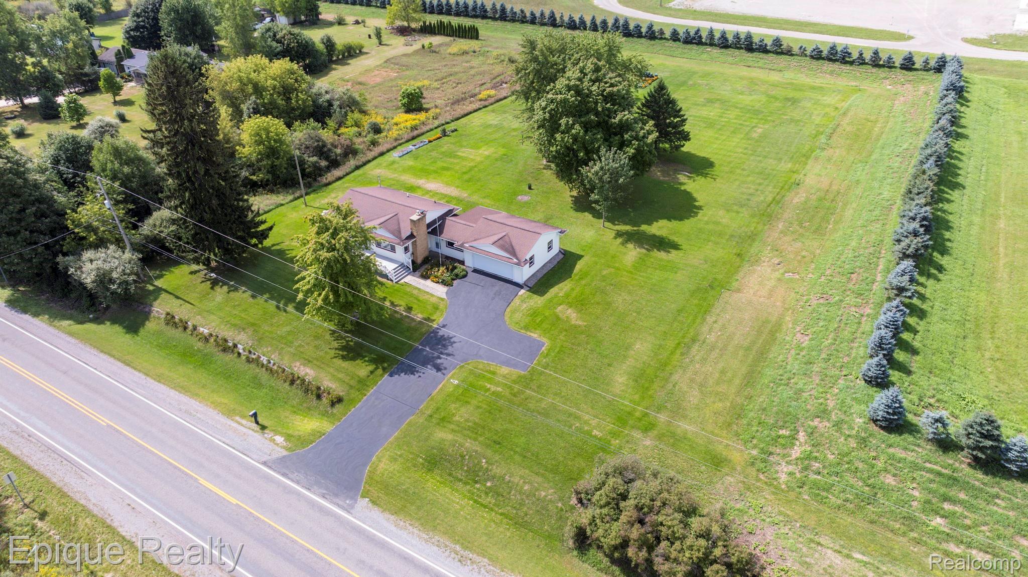 10091 North Genesee Road Mount Morris, MI 48458 - Photo 2 of 35 Expansive property featuring a asphalt driveway, attached garage, and a manicured lawn with mature trees
