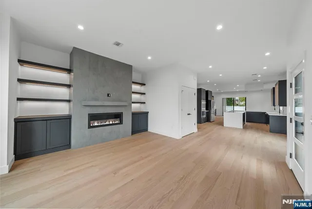 a living room with a fireplace and a walk in closet with wooden floor
