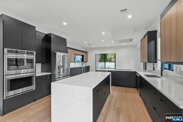 a kitchen with stainless steel appliances a refrigerator and a wooden floor
