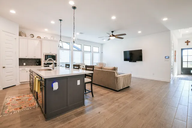 a kitchen with stainless steel appliances kitchen island granite countertop a refrigerator a stove a sink a dining table and chairs with wooden floor