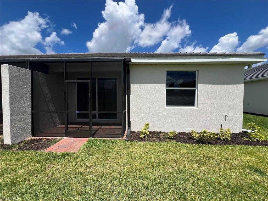 2320 Dragonfruit Way Naples, FL 34120 - Photo 24 of 33 Back of house featuring a lawn, stucco siding, and a sunroom