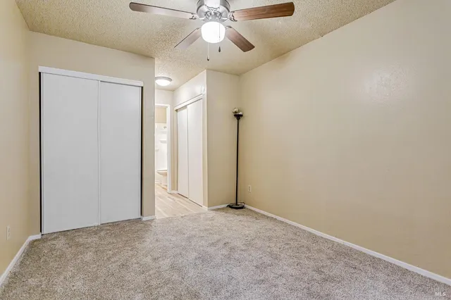 an empty room with closet and a chandelier fan
