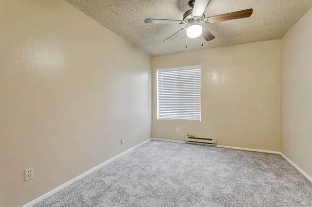 an empty room with a window and a fan