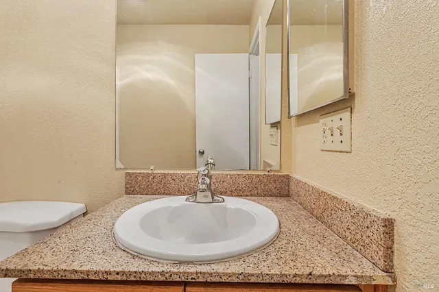 a bathroom with a granite countertop sink and a mirror
