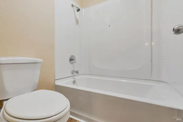 a white toilet sitting next to a bath tub