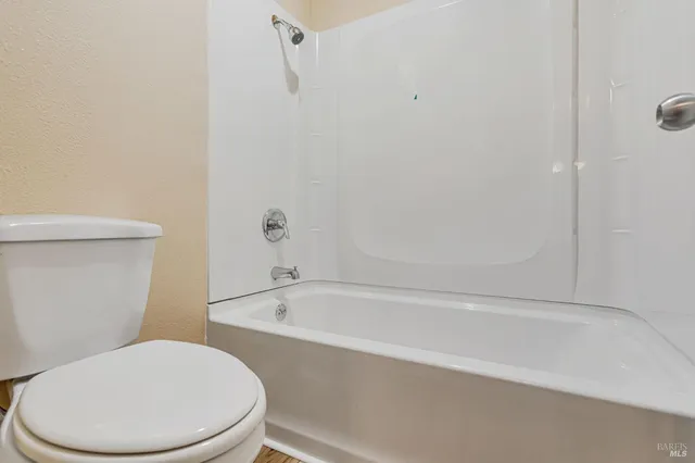 a white toilet sitting next to a bath tub