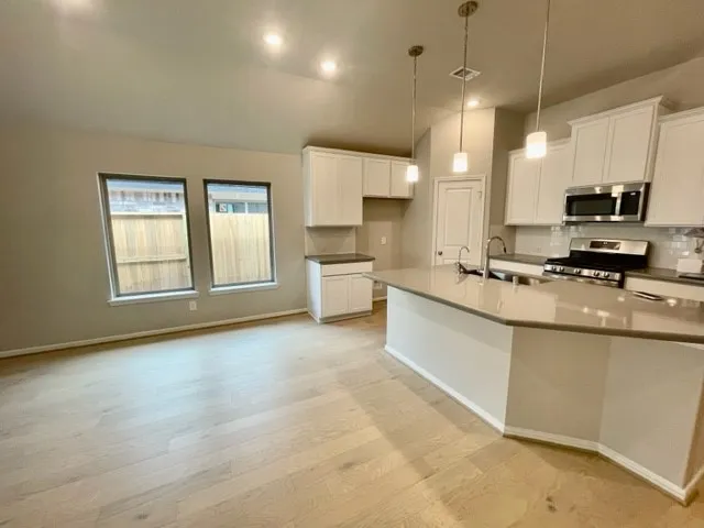 a kitchen with stainless steel appliances granite countertop white cabinets and black stove top oven with granite countertops