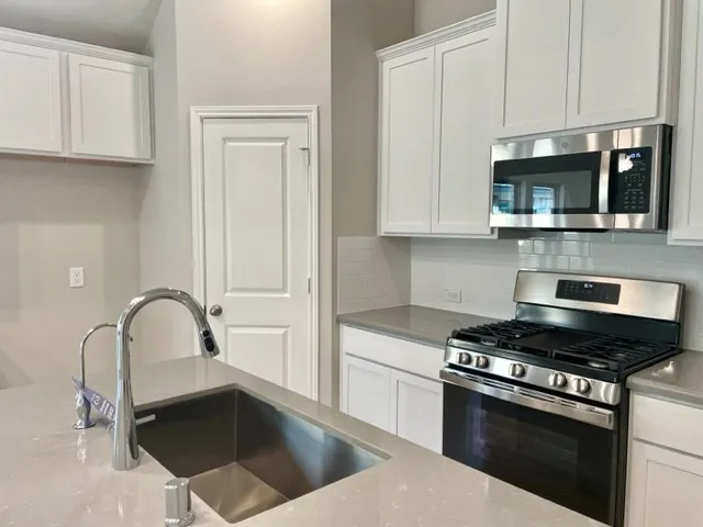 a kitchen with granite countertop a sink stainless steel appliances and cabinets