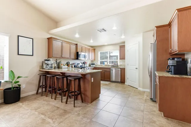 a kitchen with stainless steel appliances granite countertop a stove top oven a sink dishwasher and a microwave oven on the blue kitchen countertops