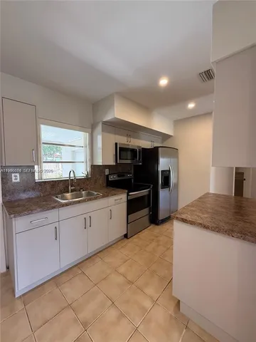 a large kitchen with granite countertop a sink and cabinets