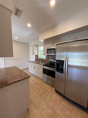 a kitchen with stainless steel appliances granite countertop a stove a sink and a refrigerator