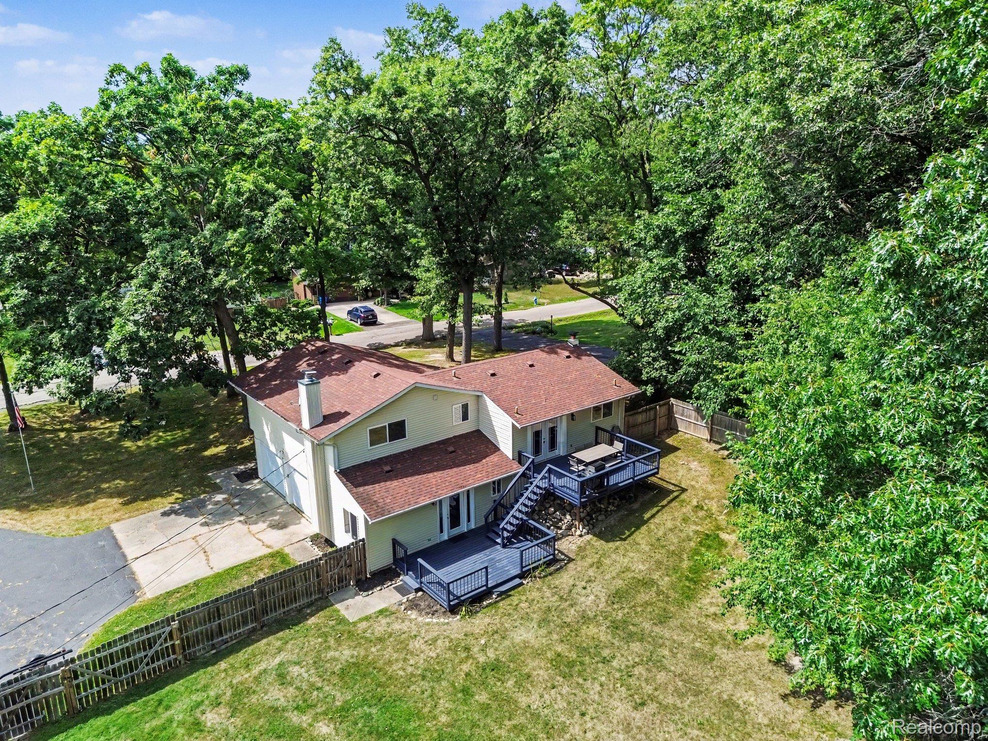 2104 Highfield Road Waterford, MI 48329 - Photo 27 of 38 Multi-level decking with stairs, expansive yard space, a two-car garage, and mature surrounding trees