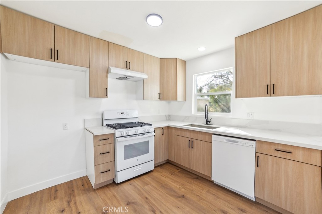 2746 Prospect Avenue Riverside, CA 92507 - Photo 6 of 10 a kitchen with stainless steel appliances granite countertop a stove a sink and white cabinets with wooden floor