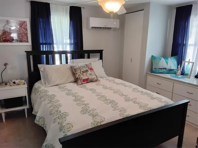 a bedroom with a bed and a flat tv screen on dresser