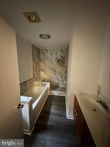 a bathroom with a tub sink and mirror