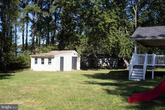 a white house that has a tree in the grass