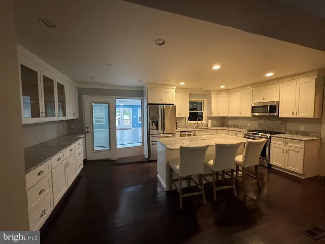 a kitchen with stainless steel appliances granite countertop a stove top oven a sink dishwasher a dining table and chairs with wooden floor